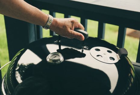 man lifting up a grill cover